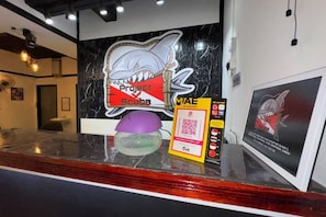 A reception desk with a shark-themed sign, a QR code, and a framed shark illustration. - Project X Scuba (Semporna)