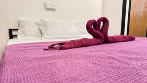 A bed with a pink textured blanket and a red towel arranged in a heart shape. - Project X Scuba (Semporna)