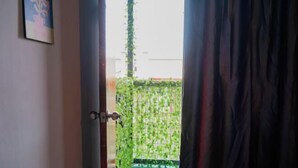 An open door leading to a balcony with a green pool and a wall covered in green vines. - Project X Scuba (Semporna)