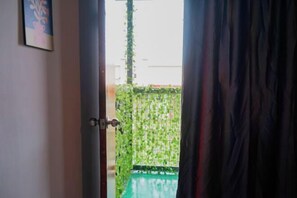 An open door leading to a balcony with a green pool and a wall covered in green vines. - Project X Scuba (Semporna)