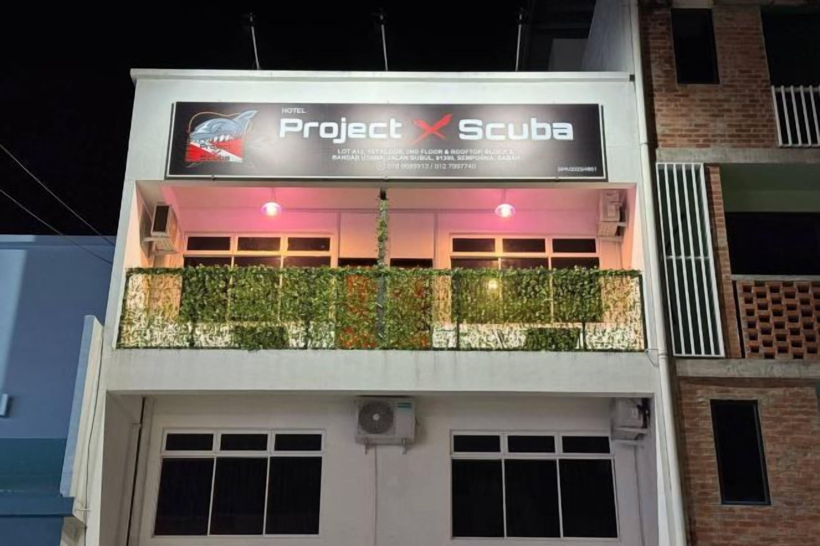 A hotel named 'Project X Scuba' with a balcony adorned with greenery.