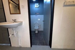 A bathroom with a white sink, a toilet, and a small mirror on the wall. - Project X Scuba (Semporna)