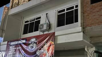 Un edificio con un gran cartel publicitario de un restaurante. Hay dos ventanas en el piso superior y una unidad de aire acondicionado montada en la pared.