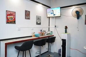 A bar area with a TV screen, posters, and a fan. - Project X Scuba (Semporna)
