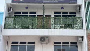 Un edificio con un letrero que dice 'Project X Scuba' y un balcón con plantas.