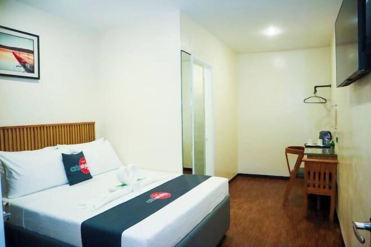 A hotel room with a bed, a desk, and a chair.