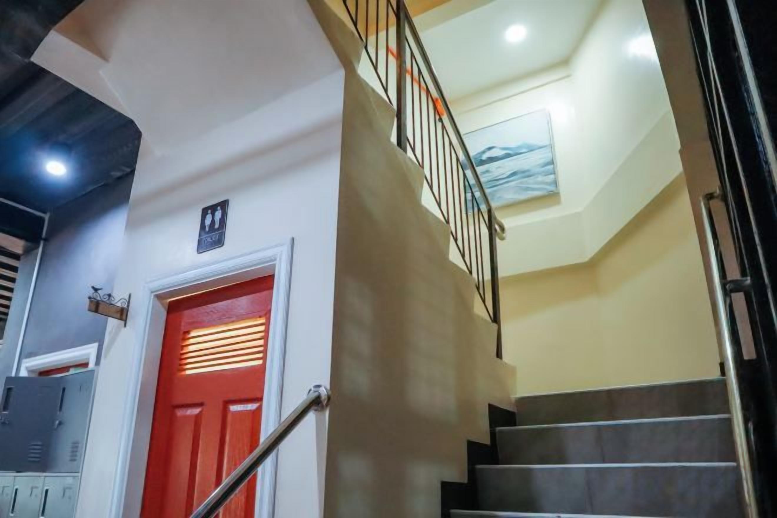 A staircase with a red door and a handrail, leading to a landing with a light fixture.