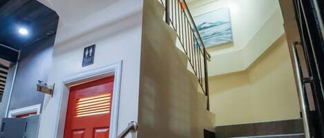 A staircase with a red door and a handrail, leading to a landing with a light fixture.