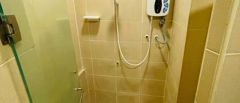 A small, tiled shower area with a glass door, a handheld showerhead, and a control panel.