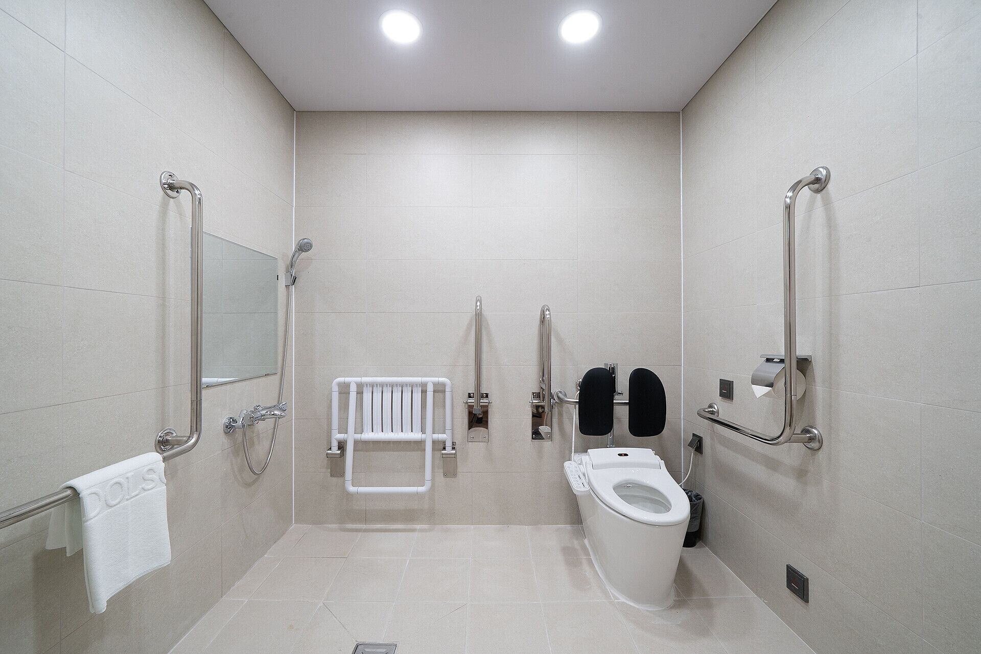 Un baño moderno con inodoro, bidé y barras de apoyo.