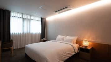 A hotel room with a bed, bedside table, lamp, and a chair.