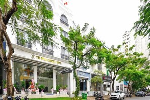 A hotel facade with a large entrance, a signboard, and a visible storefront. - The Shilla Luxury I Hotel-더신라럭셔리호텔 (Ho Chi Minh City)