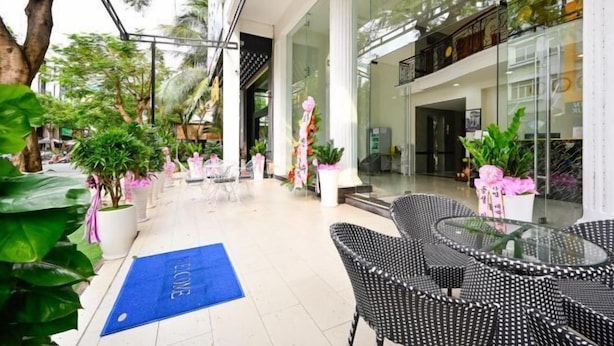 Un jardin d’intérieur avec des plantes en pot, un tapis bleu et des chaises en osier.