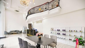 Un hall d’hôtel moderne comprenant un comptoir d’accueil, un espace salon avec une table et des chaises, et un escalier décoratif.