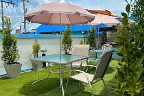 A patio with a table and chairs, surrounded by potted plants and a blue wall.