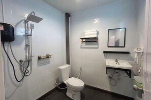 A small, modern bathroom with a toilet, a sink, a mirror, and a shower.