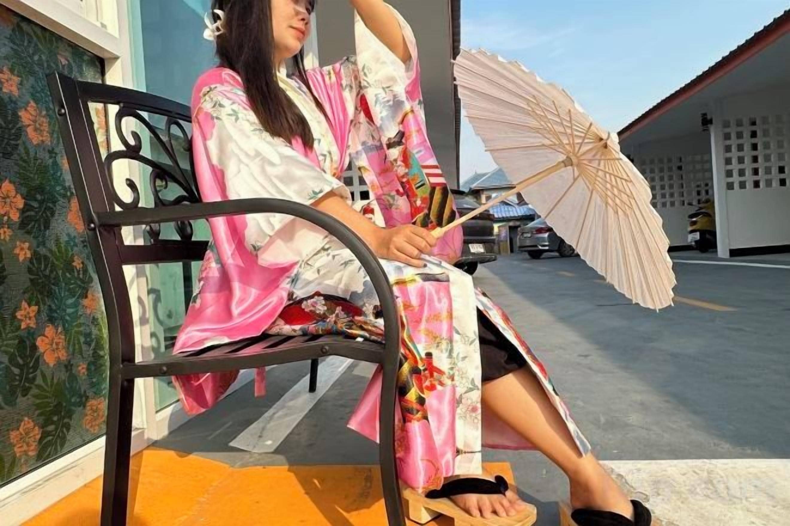 A person seated on a bench outdoors, holding an umbrella.