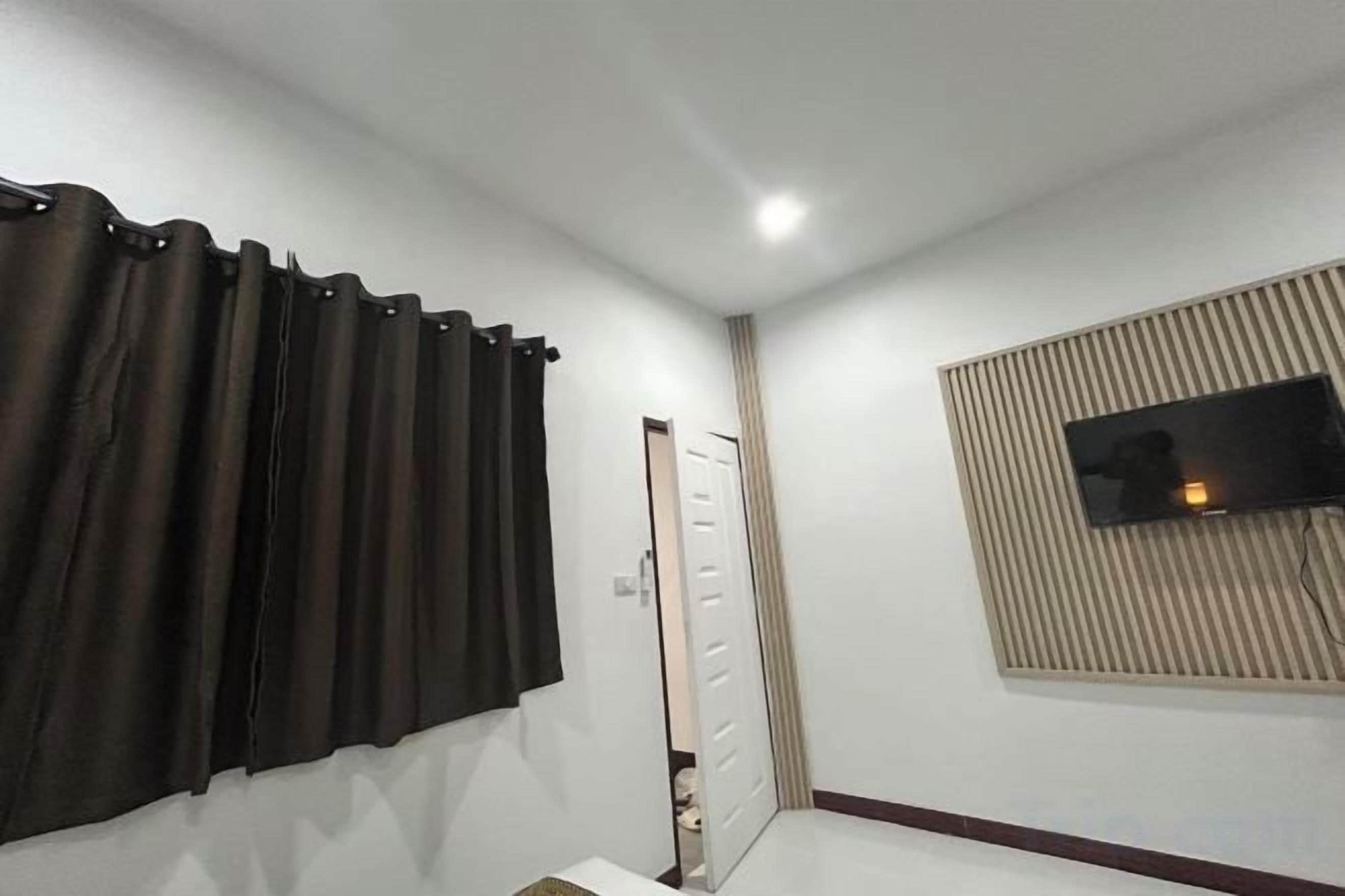 A room with a door, a window with blinds, and a wall-mounted television.