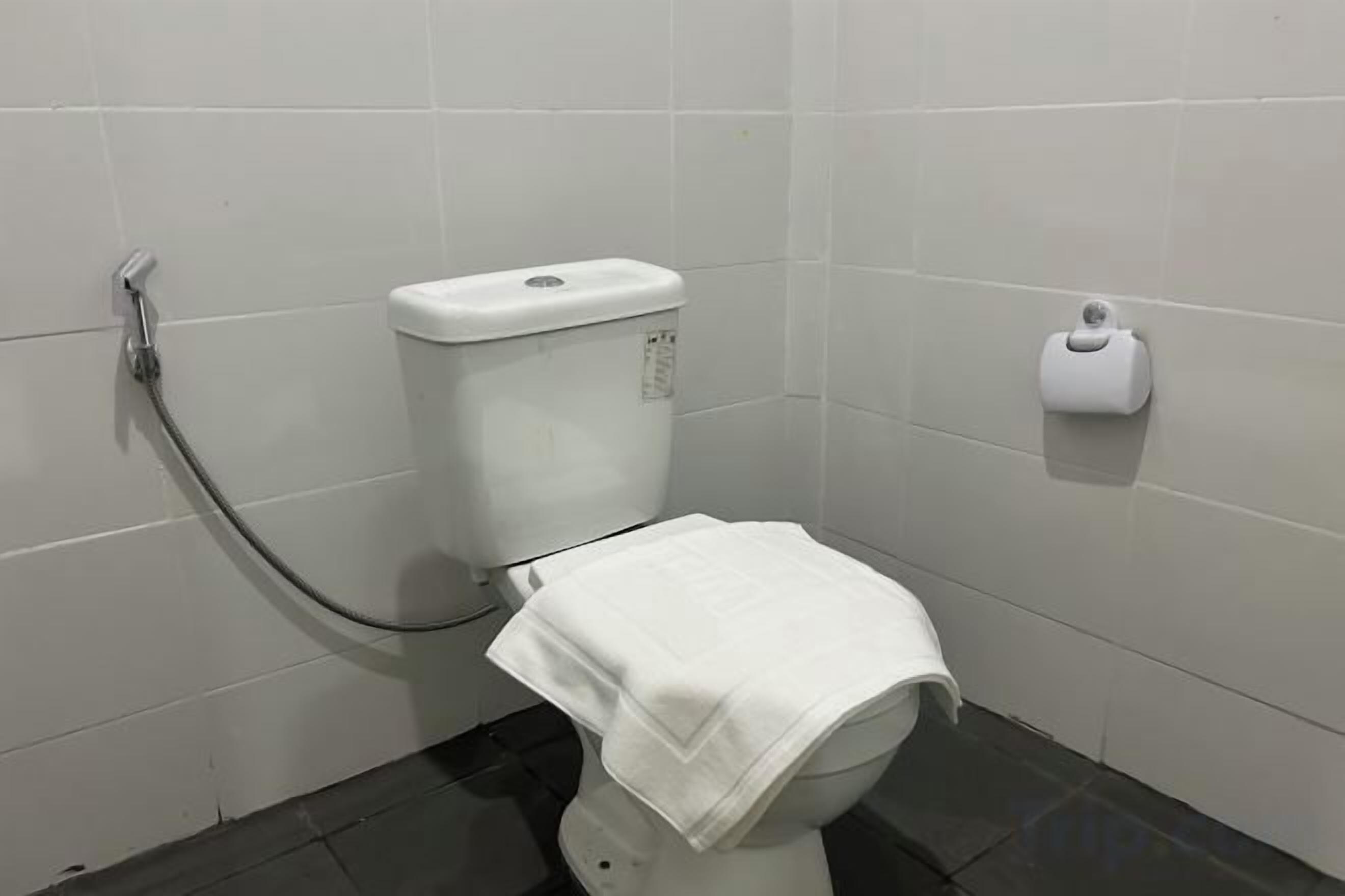 A bathroom with a toilet, a paper towel dispenser, and a toilet paper holder on the wall.