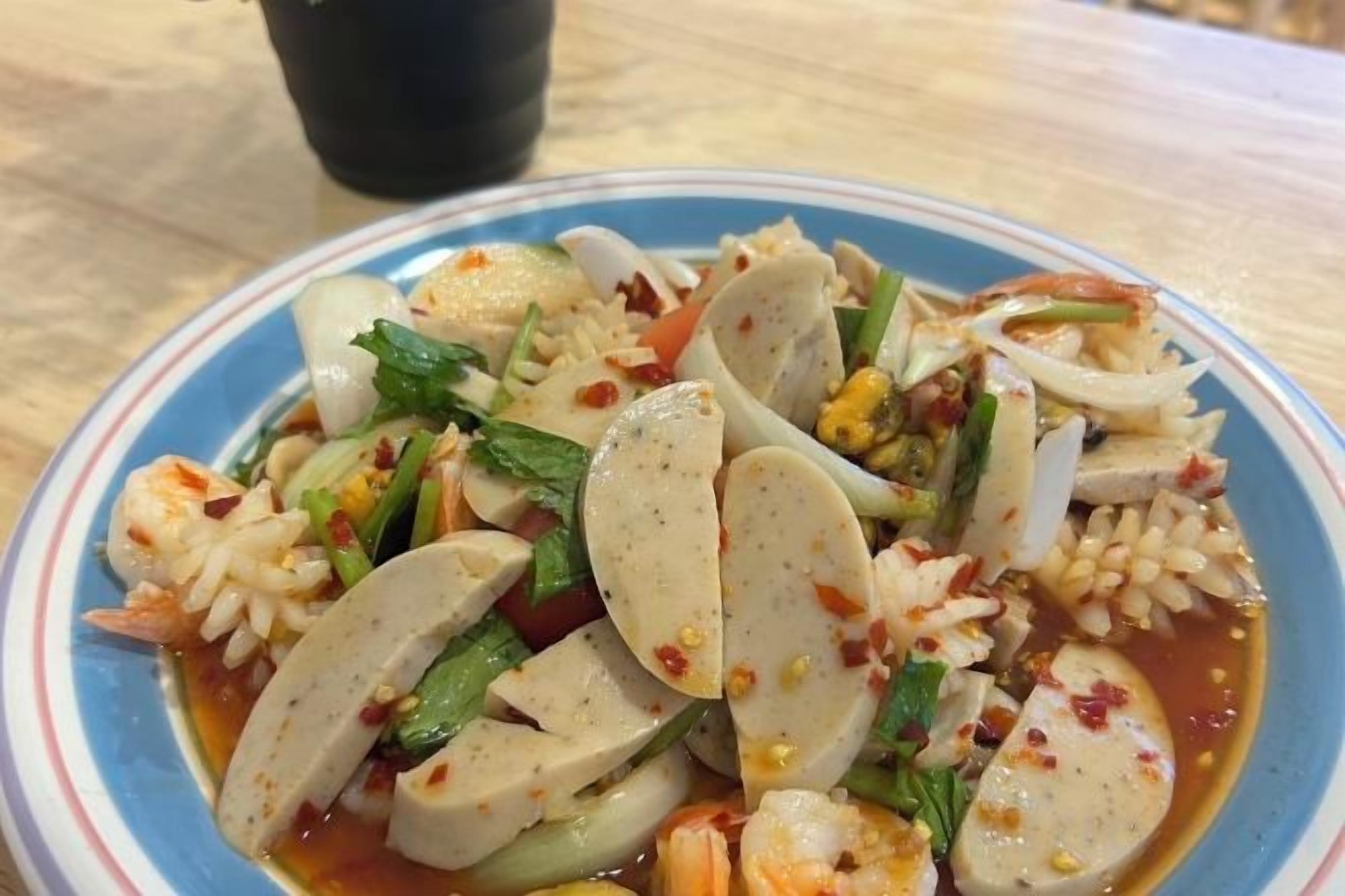 Un plato de comida con salchicha en rodajas, verduras y arroz.