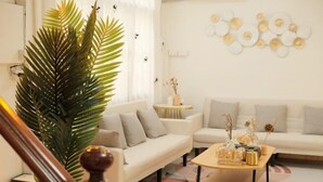 A modern living room with a sofa, a coffee table, and a large plant. - Luck viia 2 (Bangkok)