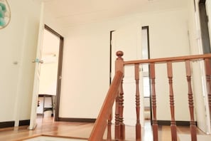 Un escalier en bois, doté d’une rampe, mène à une porte.