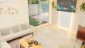 A modern living room with a white sofa, a wooden coffee table, and a flat-screen TV mounted on the wall. - Luck viia 2 (Bangkok)