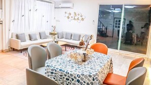 A modern living room with a sofa, chairs, and a dining table with a patterned tablecloth. - Luck viia 2 (Bangkok)