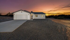 A single-story house with a garage, a driveway, and a gravel yard.