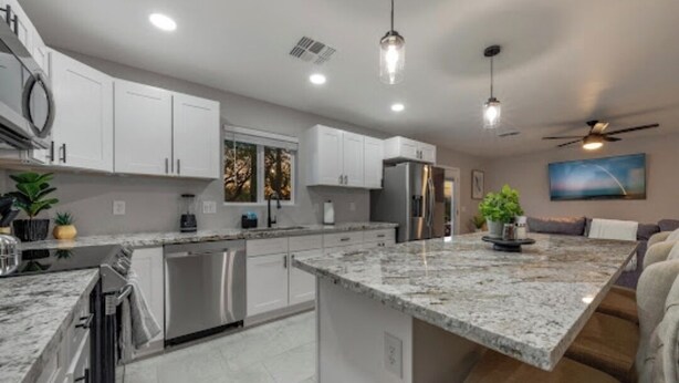 A modern kitchen with white cabinets, stainless steel appliances, and a granite countertop.