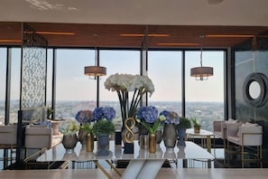 A dining area with a table set for four, large windows, and a city view.
