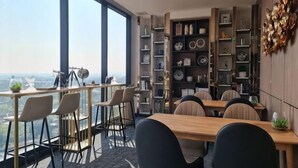 Un espace repas moderne avec une table haute et des chaises, une bibliothèque et une vue sur la ville.