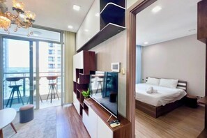Una habitación de hotel moderna con balcón, cama, televisor y zona de escritorio.