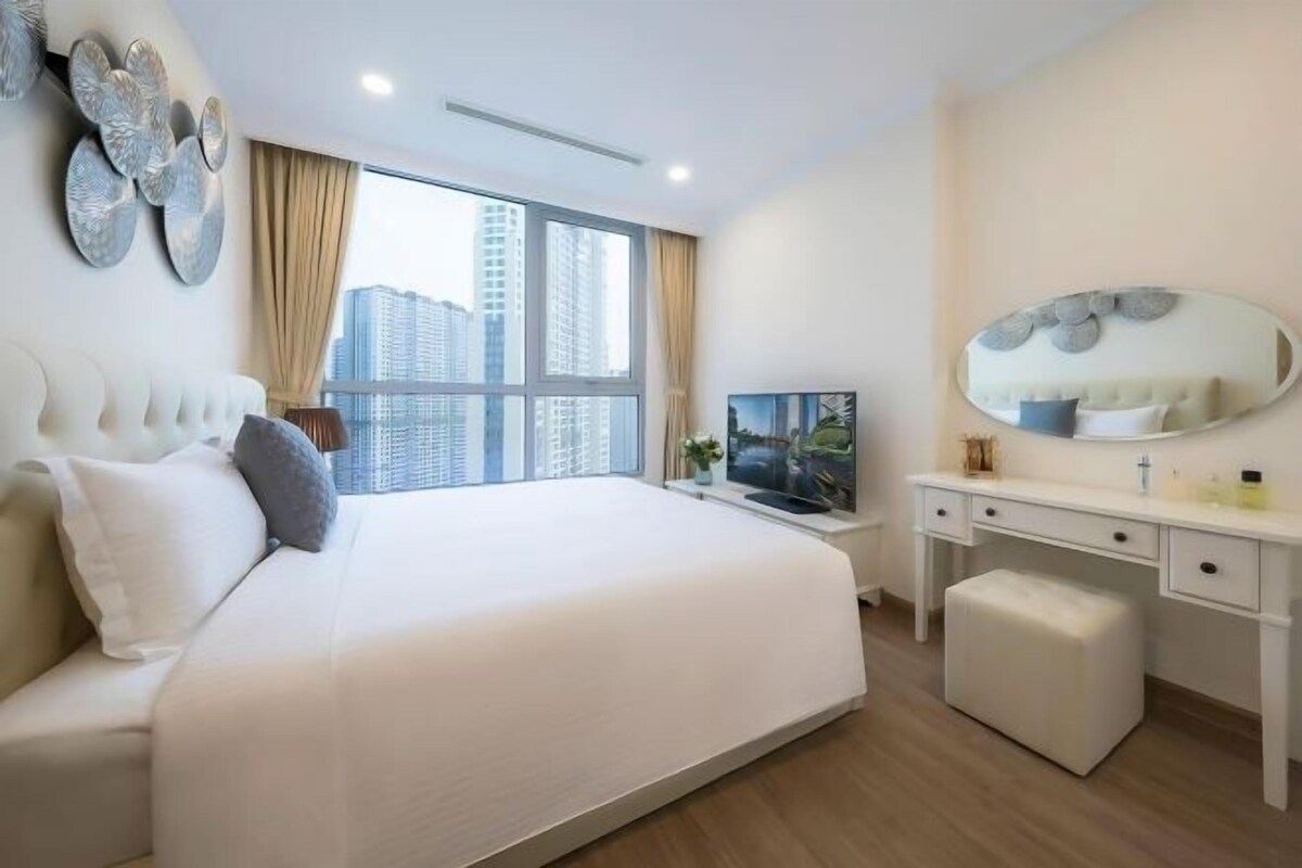 Ein modernes Hotelzimmer mit einem großen Bett, einem Schreibtisch, einem Spiegel und einem Fenster mit Blick auf die Stadt.
