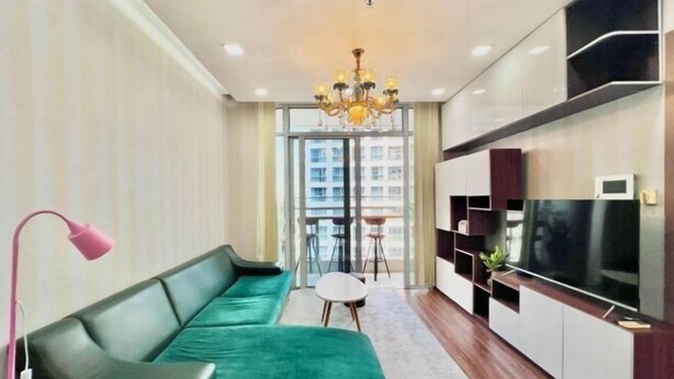 A modern living room with a green sofa, a TV, and a chandelier.