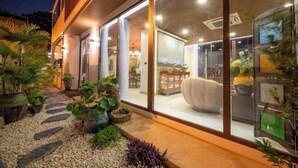 A modern house with a glass facade, outdoor seating area, and potted plants. - Alden Design Pool Villa (Pattaya)