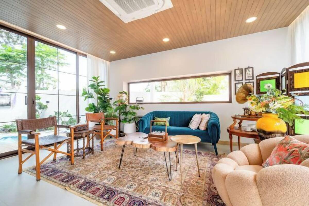 Ein modernes Wohnzimmer mit einem blauen Sofa, Holzstühlen, einem Couchtisch und einem gemusterten Teppich.