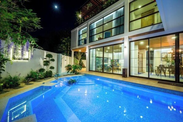 A modern two-story building with a swimming pool in the foreground.