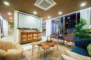 A modern living room with a projector screen, seating, and a large window.