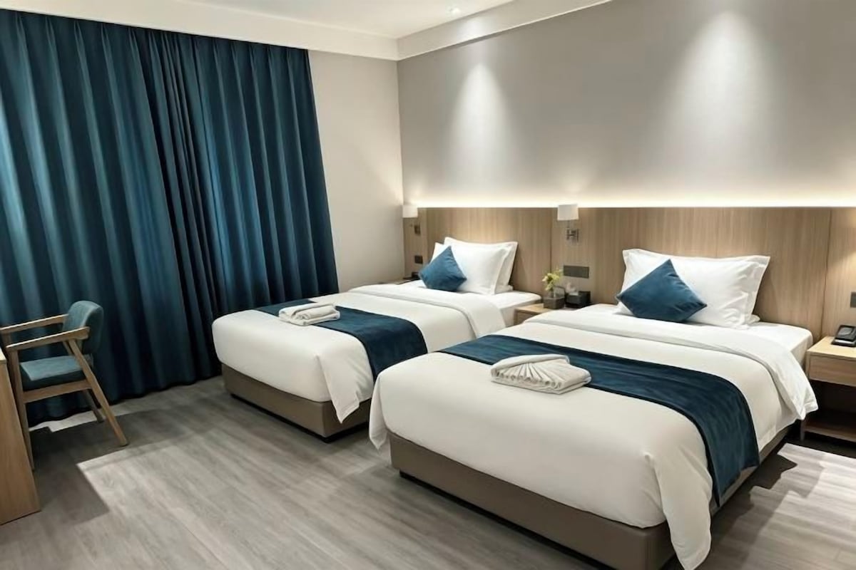 A hotel room with two beds, a desk, and a chair.
