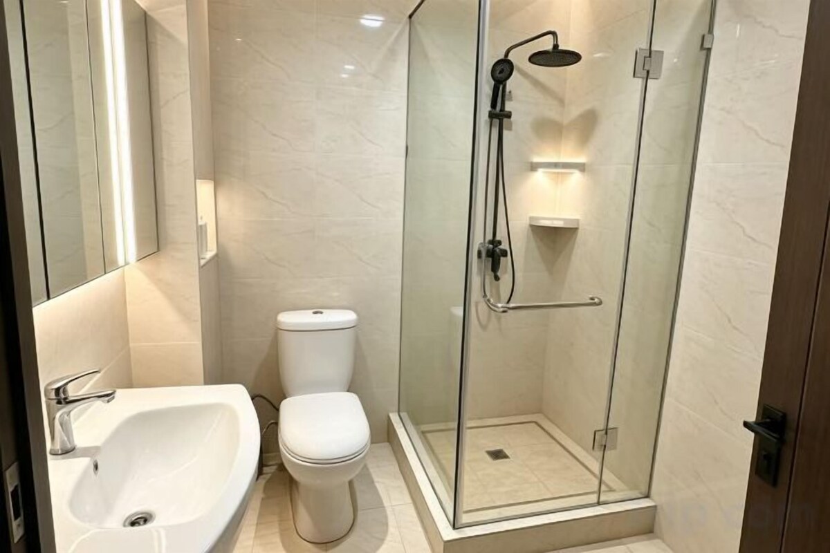 A modern bathroom with a glass-enclosed shower, a white toilet, and a sink.