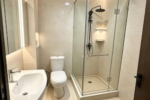 A modern bathroom with a glass-enclosed shower, a white toilet, and a sink. - AERON Hotel (Tashkent)