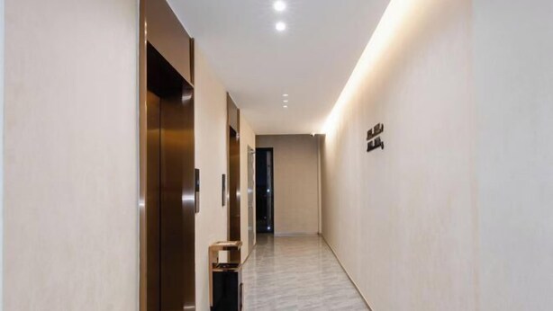A modern hallway with a marble floor, a trash bin, and a door with a sign. - New Junlong Hotel (Bavet)
