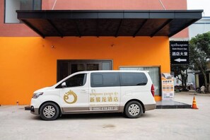 A white van parked in front of a building with a signboard. - New Junlong Hotel (Bavet)