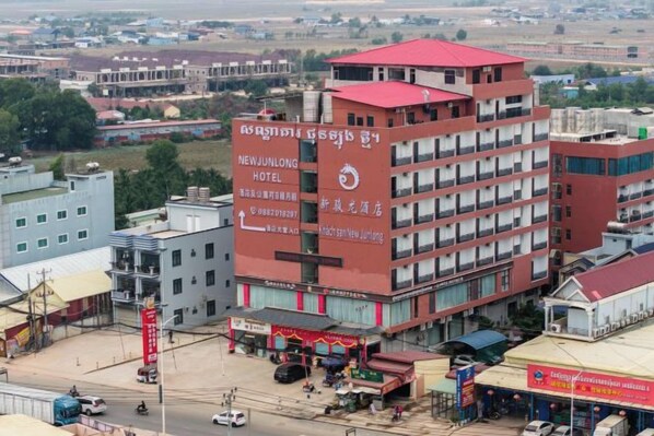 A multi-story hotel with a red roof and signage for 'NEWJUNLONG HOTEL'.