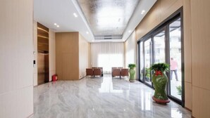 A spacious lobby with a polished marble floor, a seating area with chairs, and large windows offering a view outside. - New Junlong Hotel (Bavet)