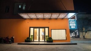 A building with a large entrance, a covered walkway, and a sign with illuminated text. - New Junlong Hotel (Bavet)