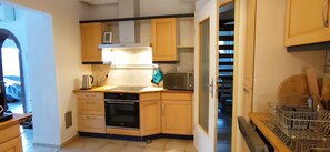 A compact kitchen with wooden cabinets, a built-in microwave, and a dishwasher. - Activity country house near the Baltic Sea with pool & orchard, for family & friends (Lübow)