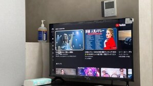 A television displaying a YouTube channel with Japanese text, a bottle of hand sanitizer, and a tissue box on a table. - Tokyo guest (Tokyo)