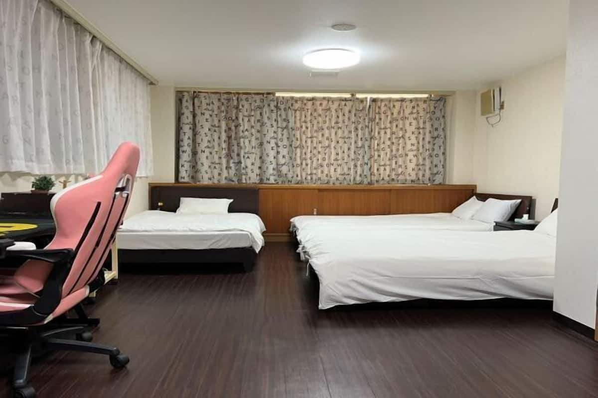 Ein Hotelzimmer mit zwei Betten, einem Schreibtisch mit Stuhl und einem Fenster mit Vorhängen.